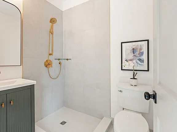 Bathroom renovation with a walk-in shower and brass fixtures by KNT Construction